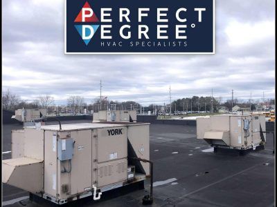 Commercial HVAC units on a flat roof under a cloudy sky with the Perfect Degree logo.