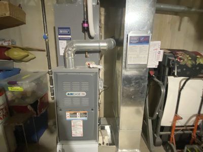 Furnace in a basement, with ductwork and surrounding storage.