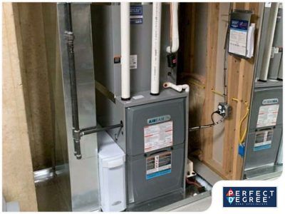 Furnace unit installed in a utility closet with ductwork and PVC piping.