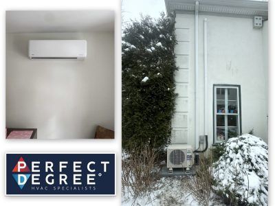 White mini-split AC inside a home, with outdoor compressor unit mounted on exterior wall. Snow on the ground.