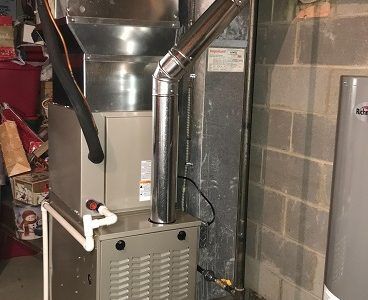 Furnace and ductwork in a basement setting, connected to a metal chimney.