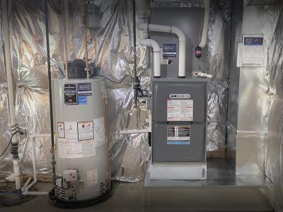 A water heater and furnace unit in a utility room with silver insulation.