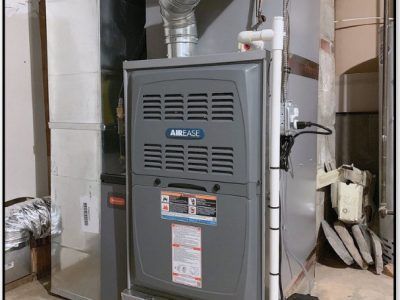 A gray Airease furnace in a basement. Ductwork and white pipes are visible.