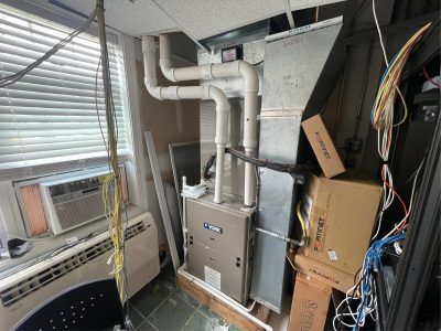 HVAC system in a cluttered utility room with an air conditioner and boxes.