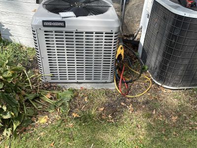 Air conditioning unit outside a building, with hoses attached.