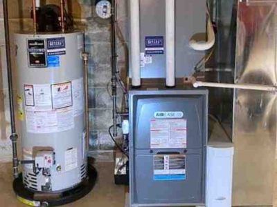 Water heater and furnace in a basement. The furnace has two white vent pipes.