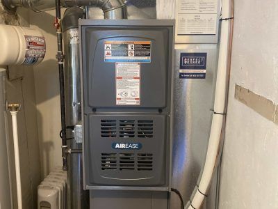 Furnace unit in a basement setting with ductwork and a water heater.
