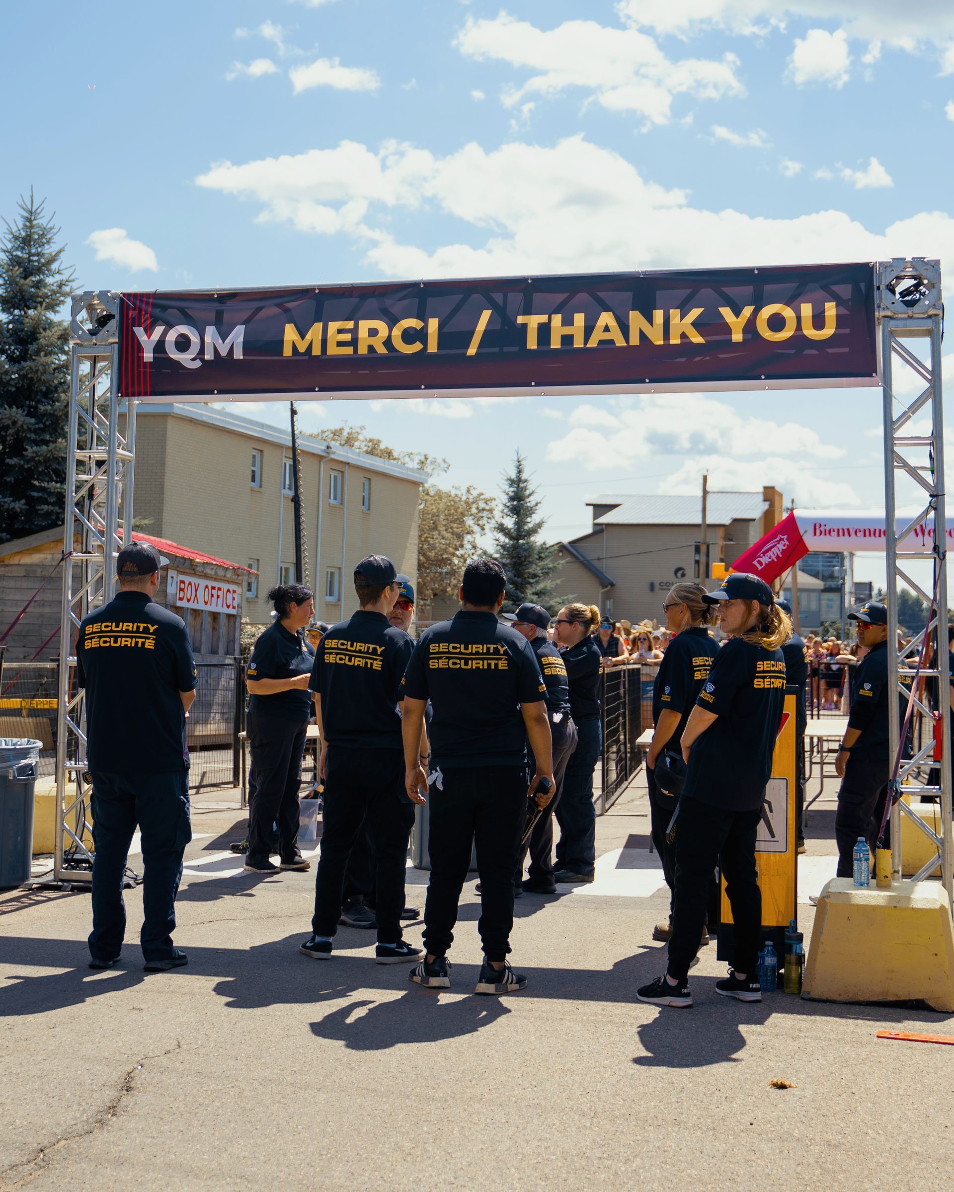 A group of people are standing under a sign that says ycm merci thank you