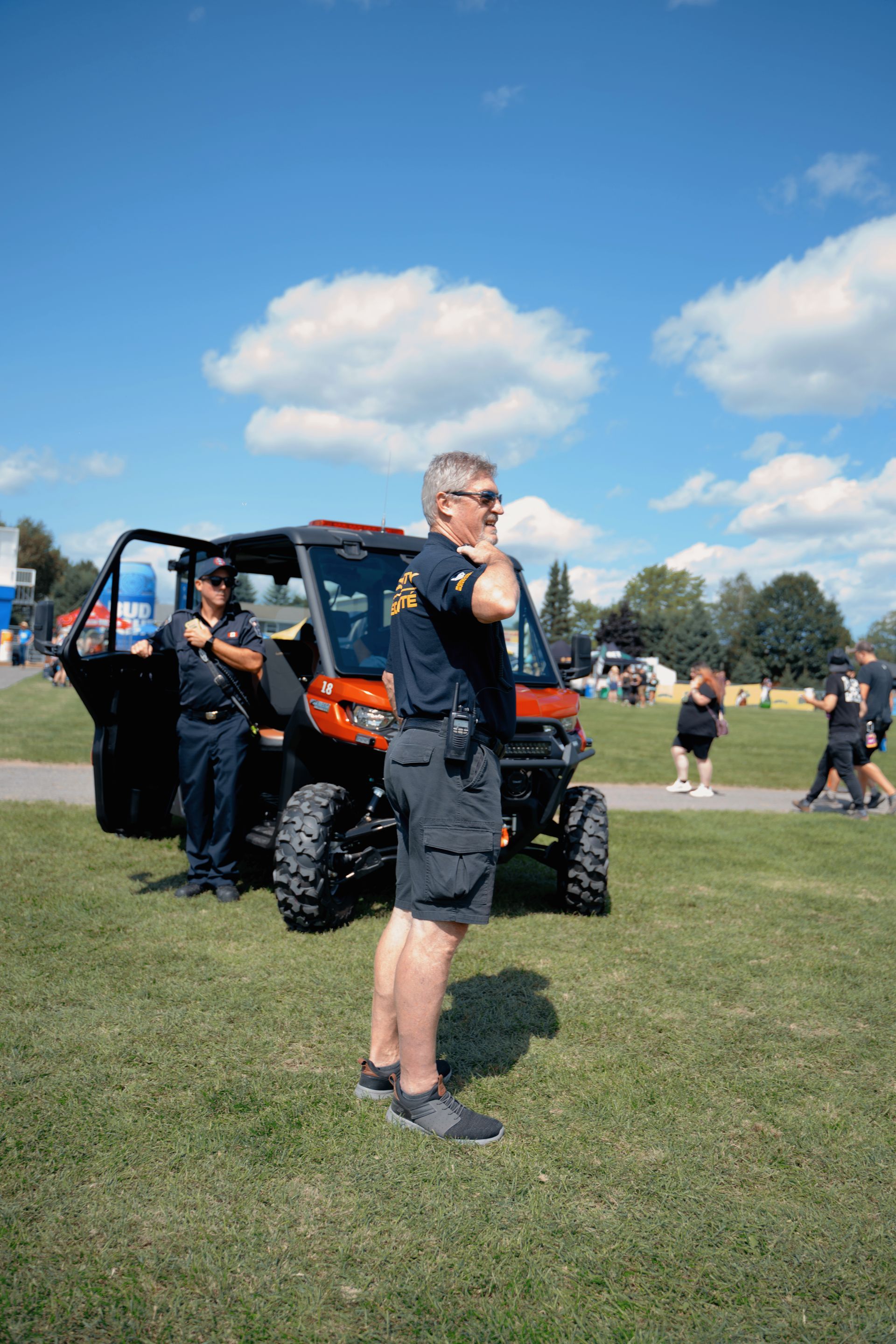 A man is standing in front of a atv in a field.