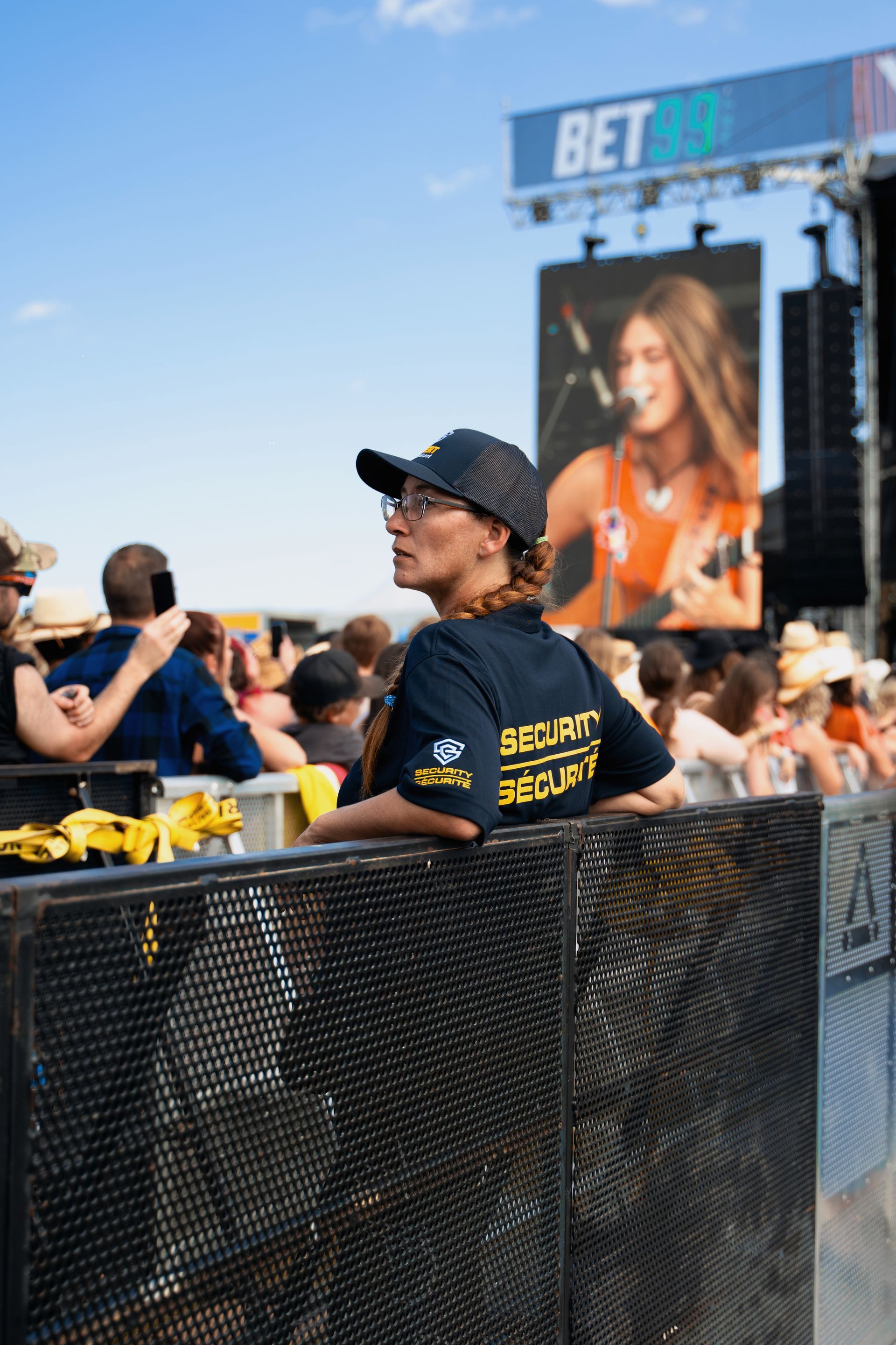 A woman in a security uniform is standing in front of a crowd at a concert.