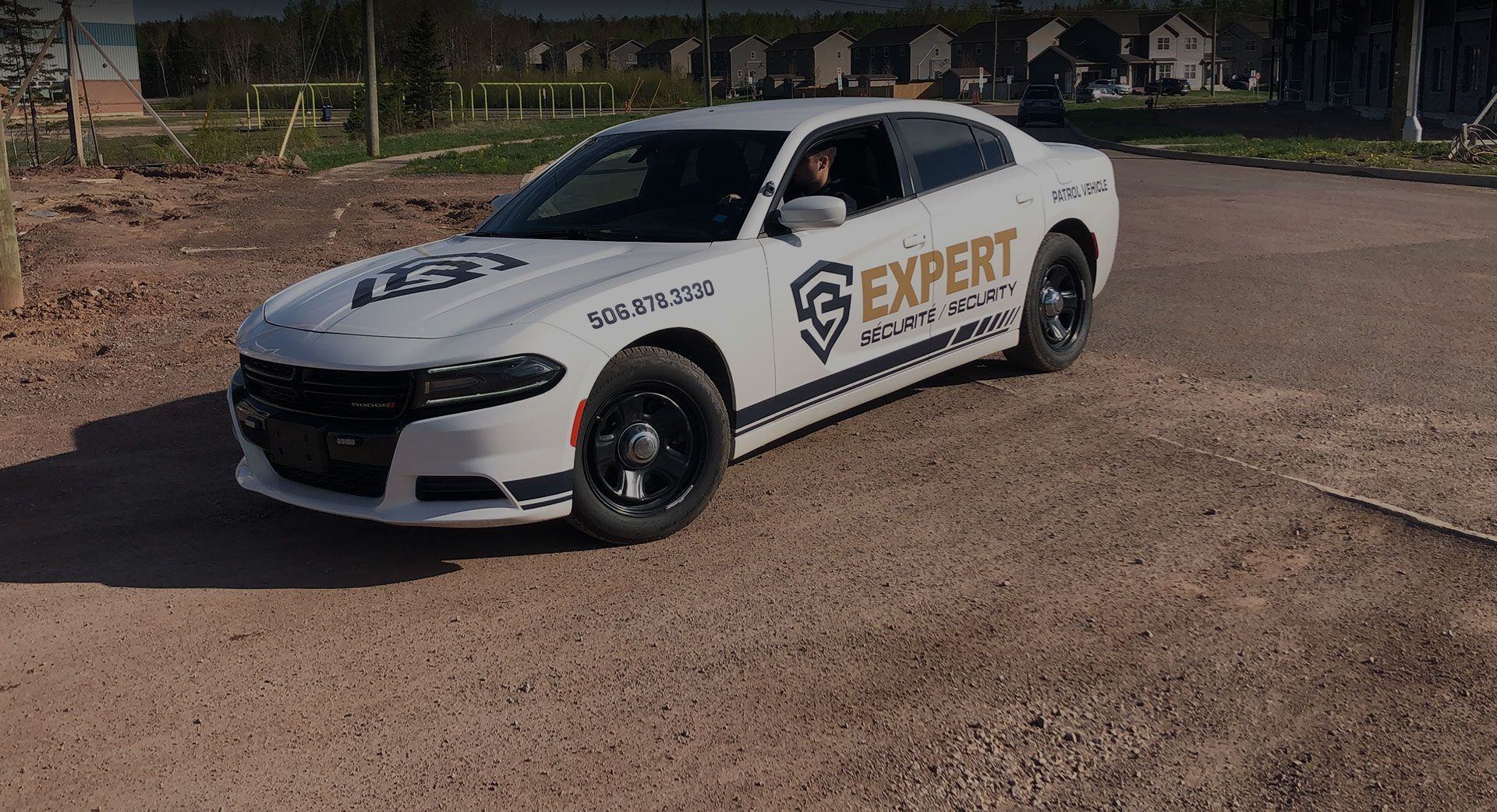 A white car with the word expert on the side is parked on a dirt road.