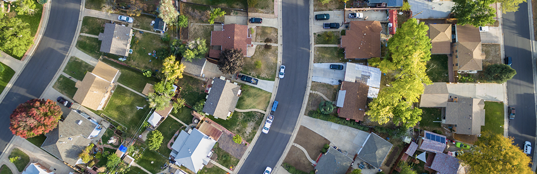 Aerial view of suburban neighborhood with houses, trees, and roads.