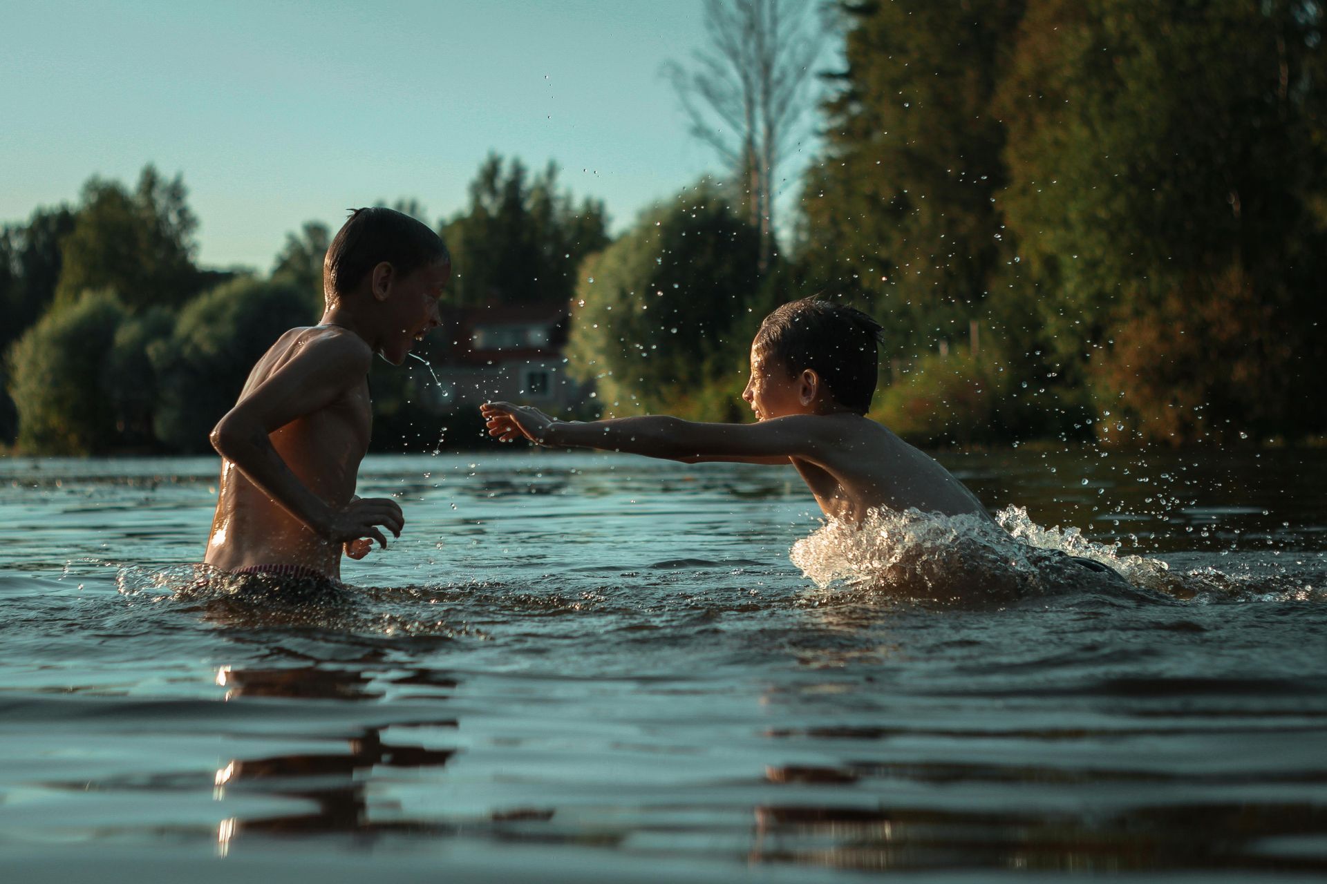 Two young boys are playing in a lake.