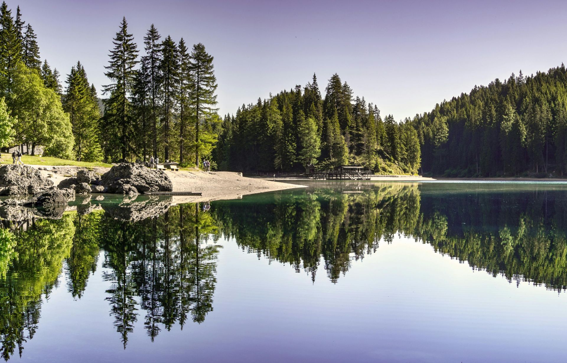 A lake with trees on the shore and trees reflected in the water