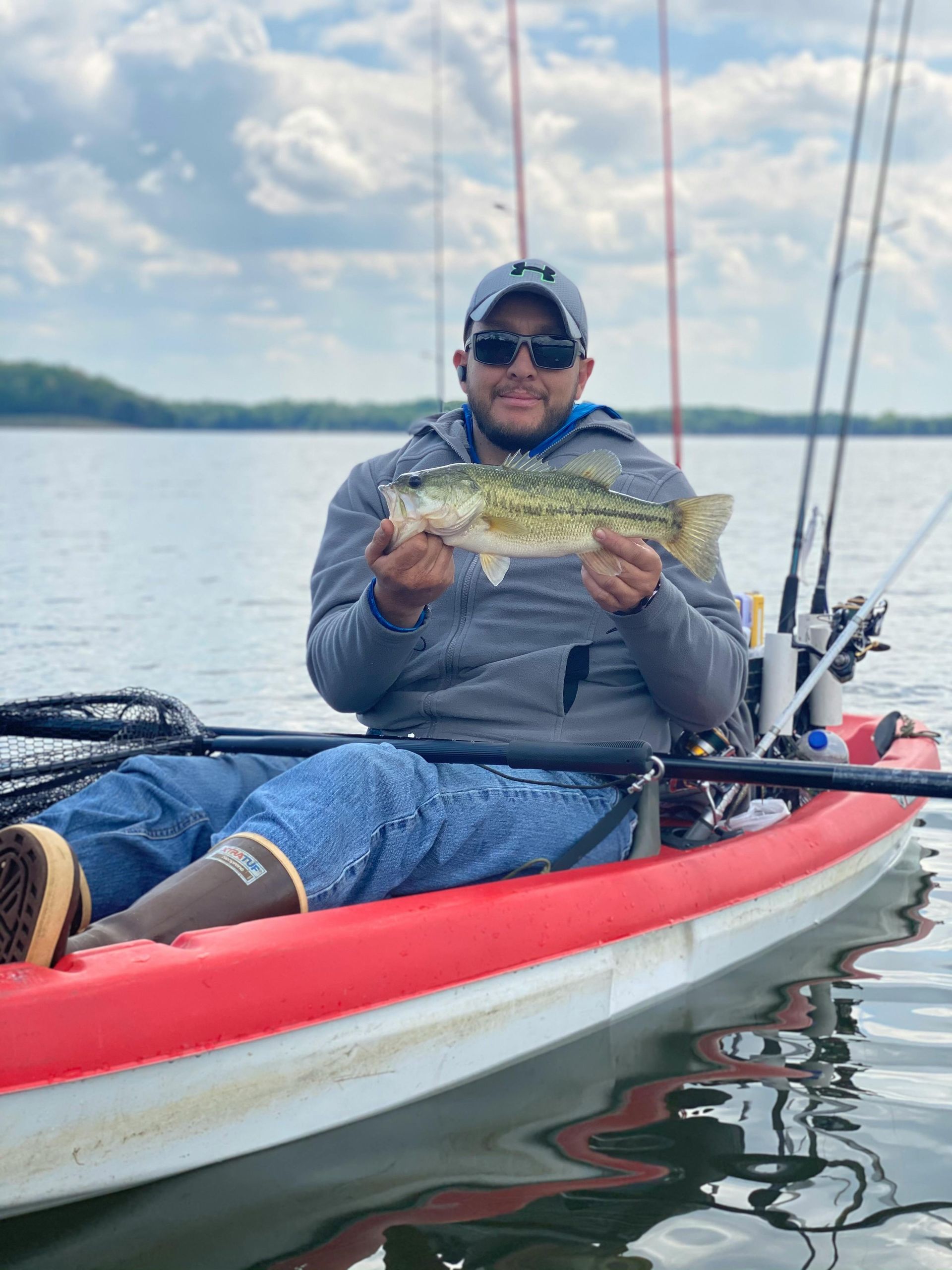 A man is sitting in a kayak holding a fish.