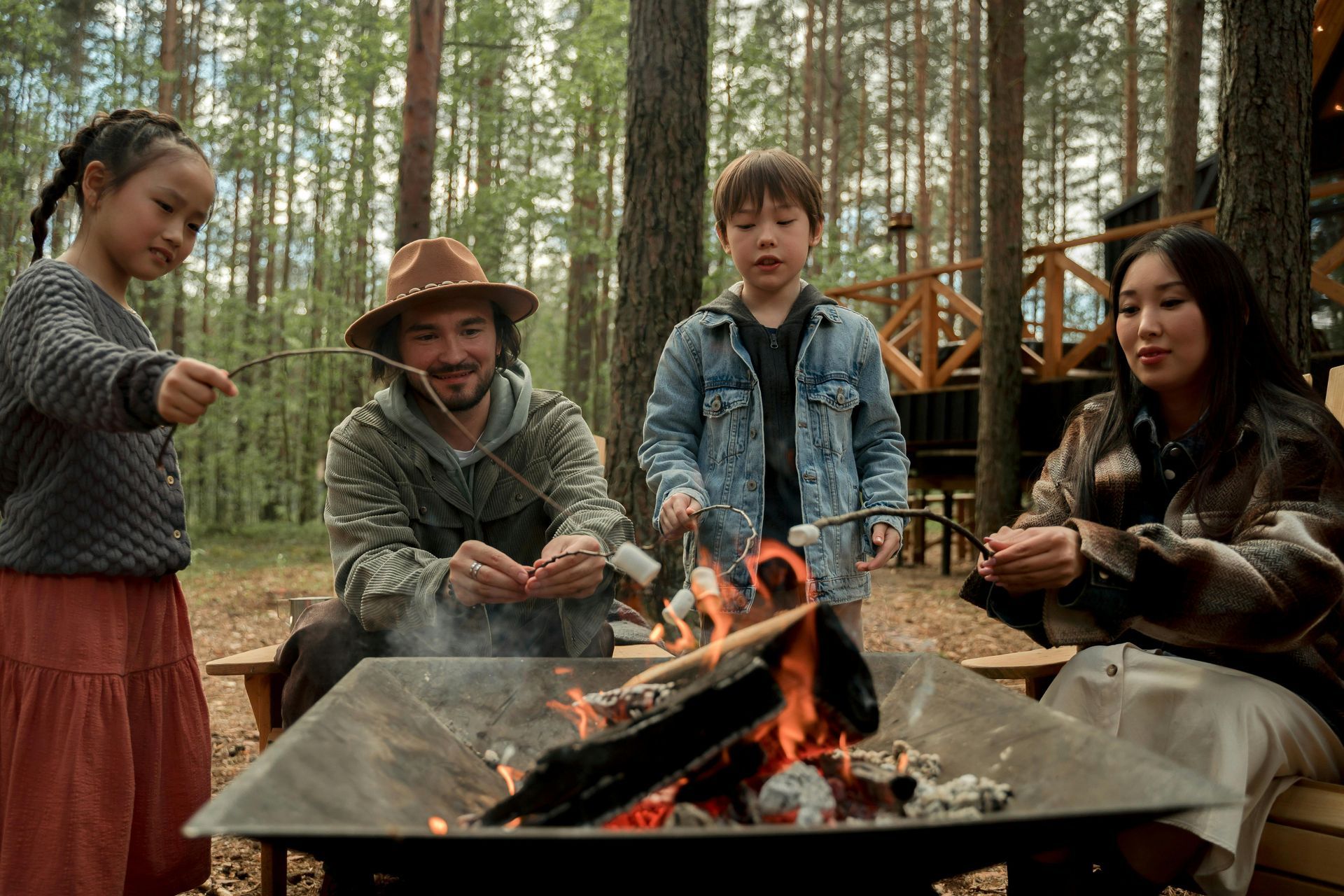 A family is roasting marshmallows over a fire pit in the woods.