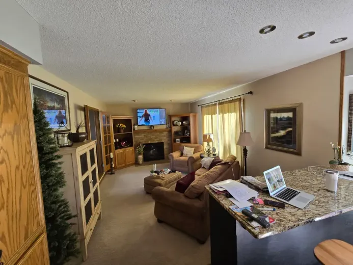 Living room with a sectional sofa, fireplace, and kitchen counter.