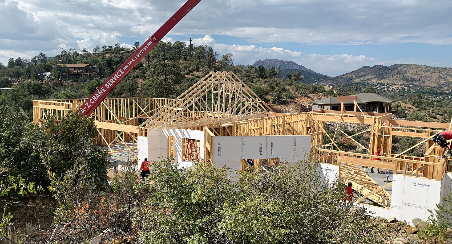 Framing stage of the Perfect Place custom home in Prescott, AZ, with a crane lifting materials into place on this custom-built structure