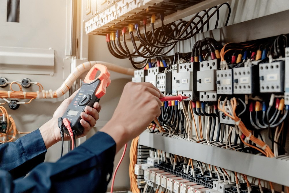 a man is using a clamp meter to check a circuit board