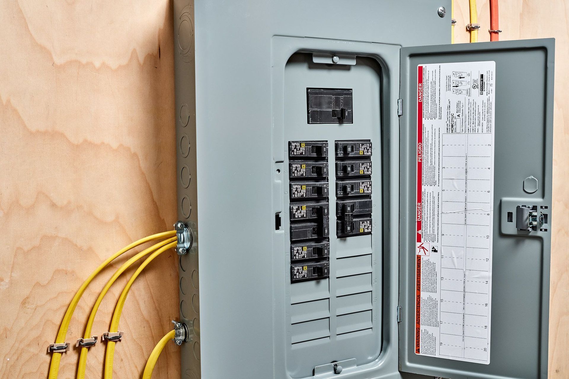 A close up of a electrical box on a wooden wall with the door open.