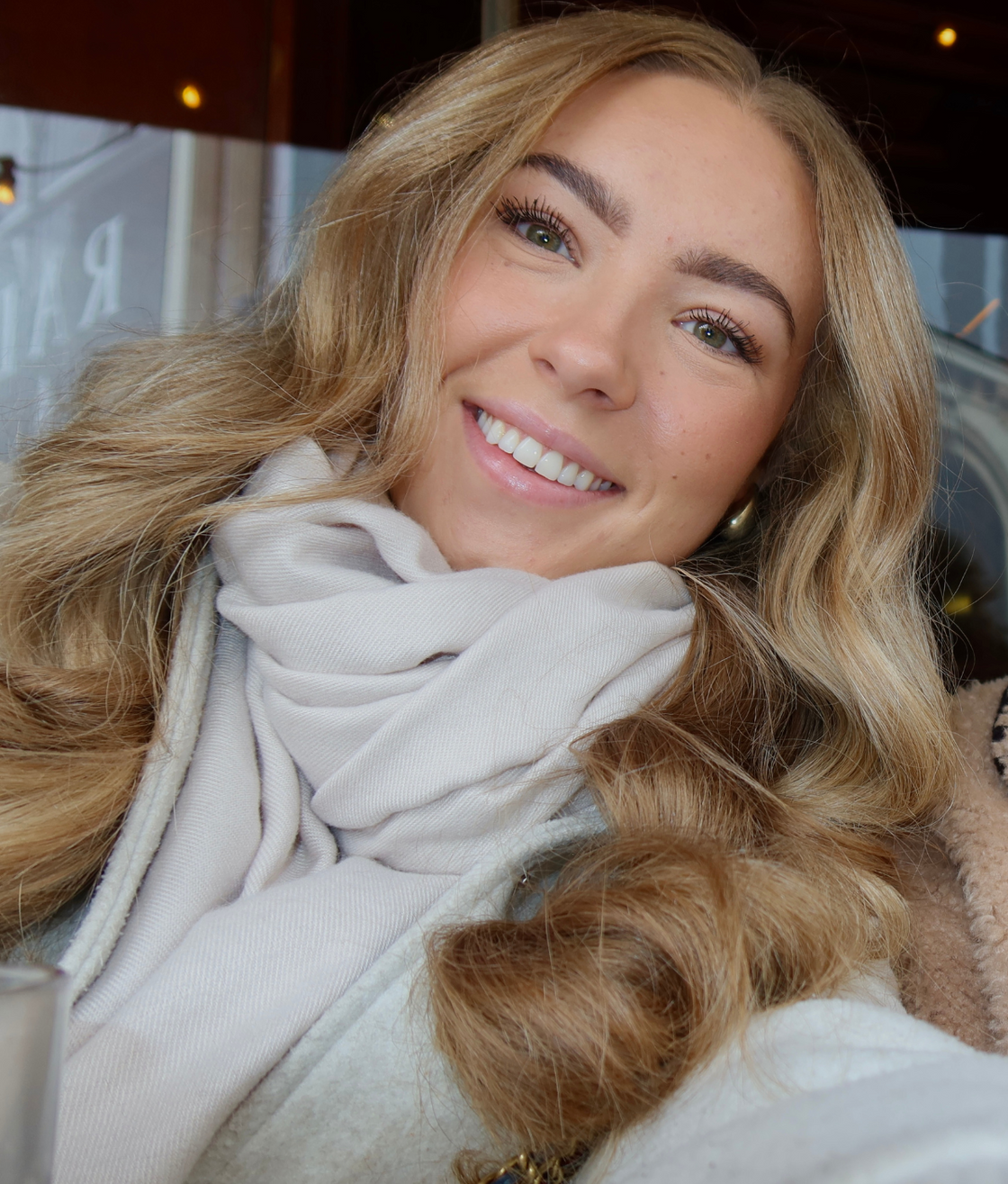 De vrouw draagt ​​een sjaal om haar nek en lacht.