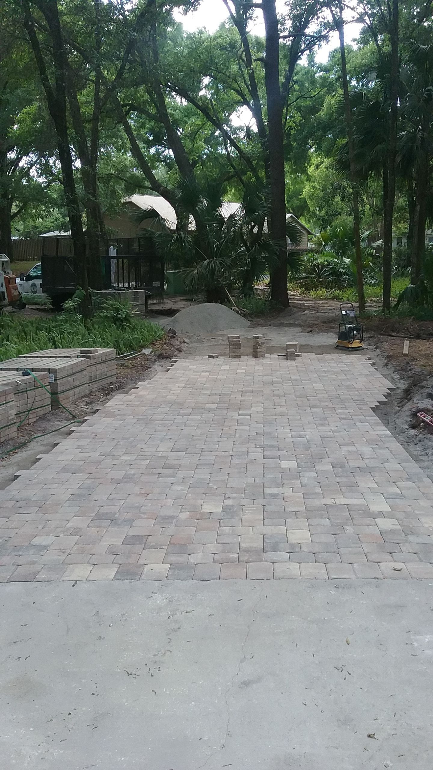 A brick driveway leading to a house in the woods.
