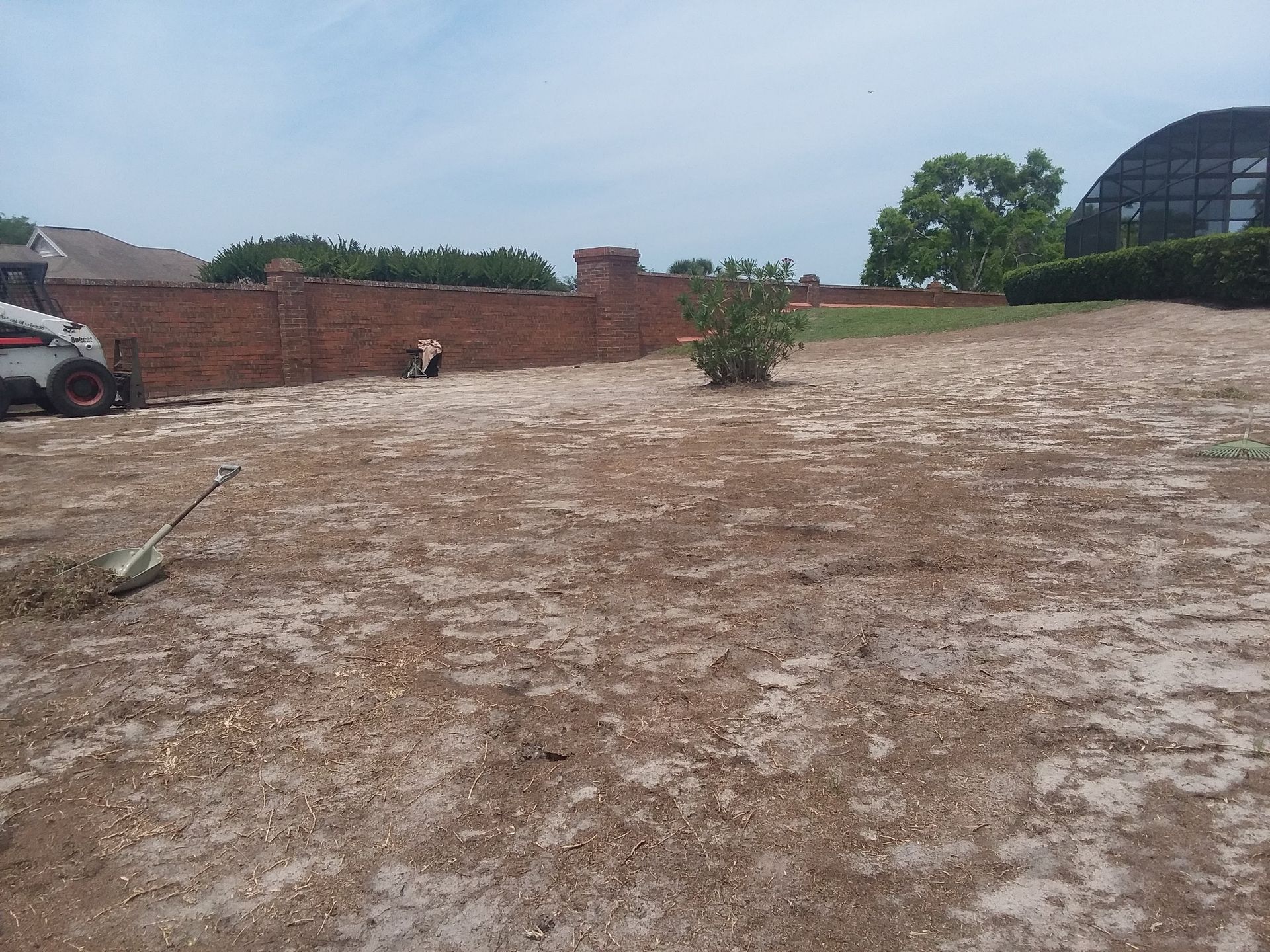 A large dirt field with a brick wall in the background.