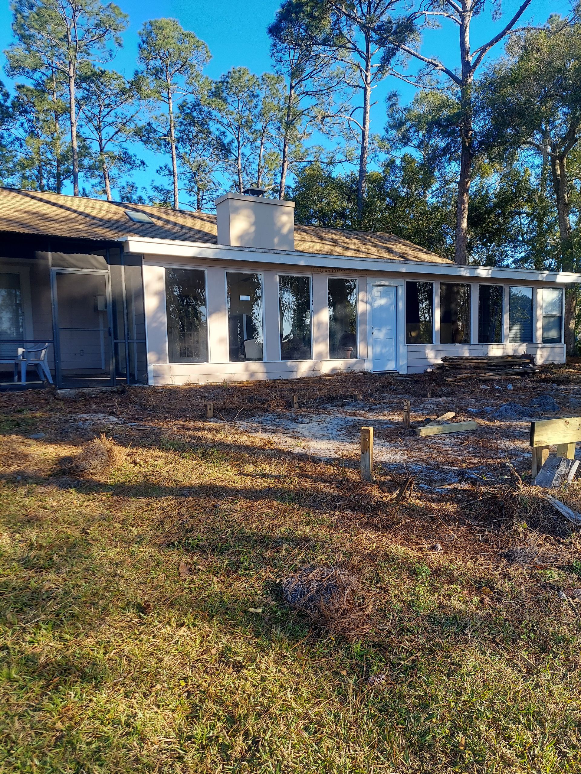 A house with a lot of windows is surrounded by trees.