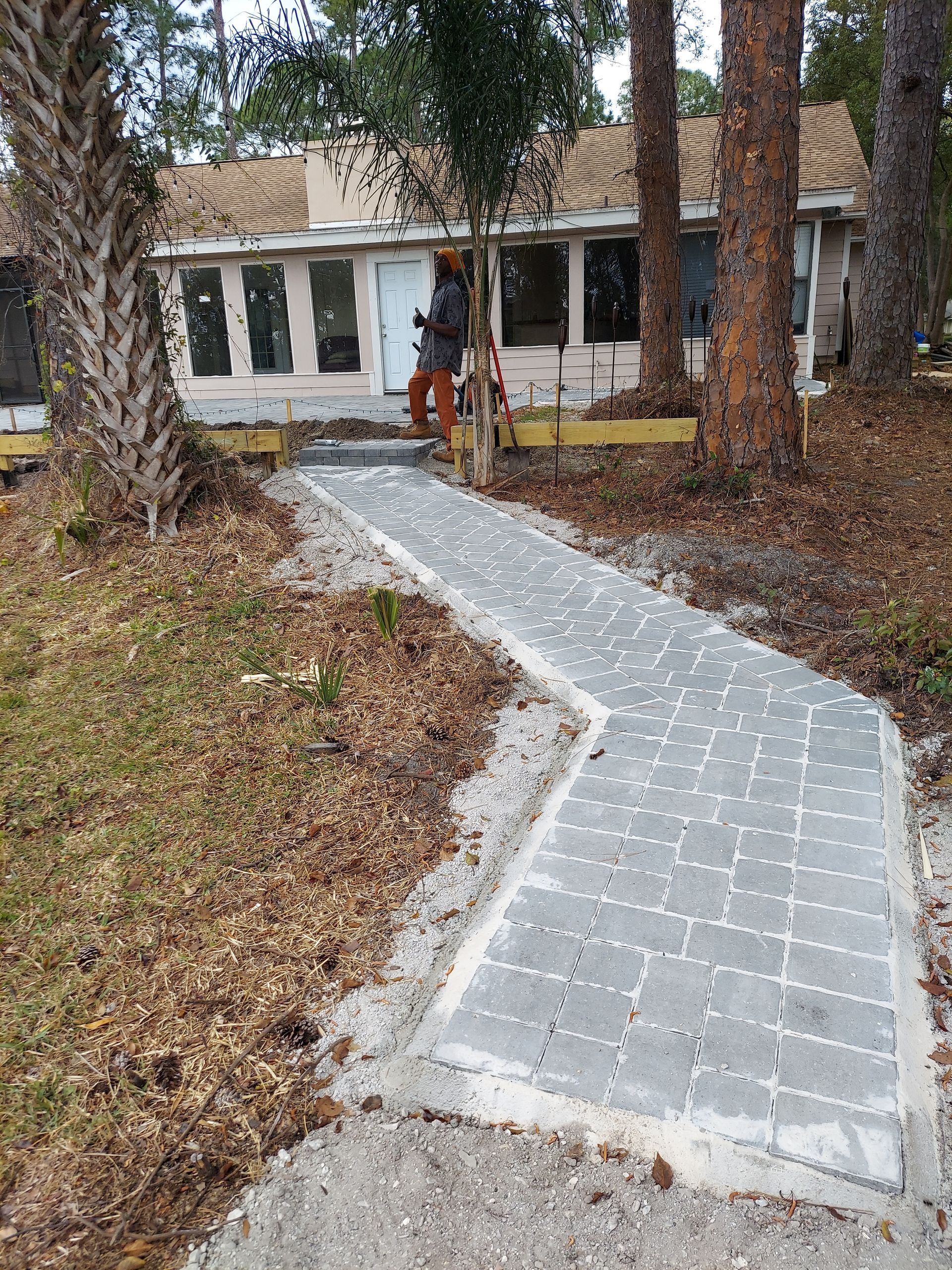 A brick walkway in a garden with a stone bench in the middle