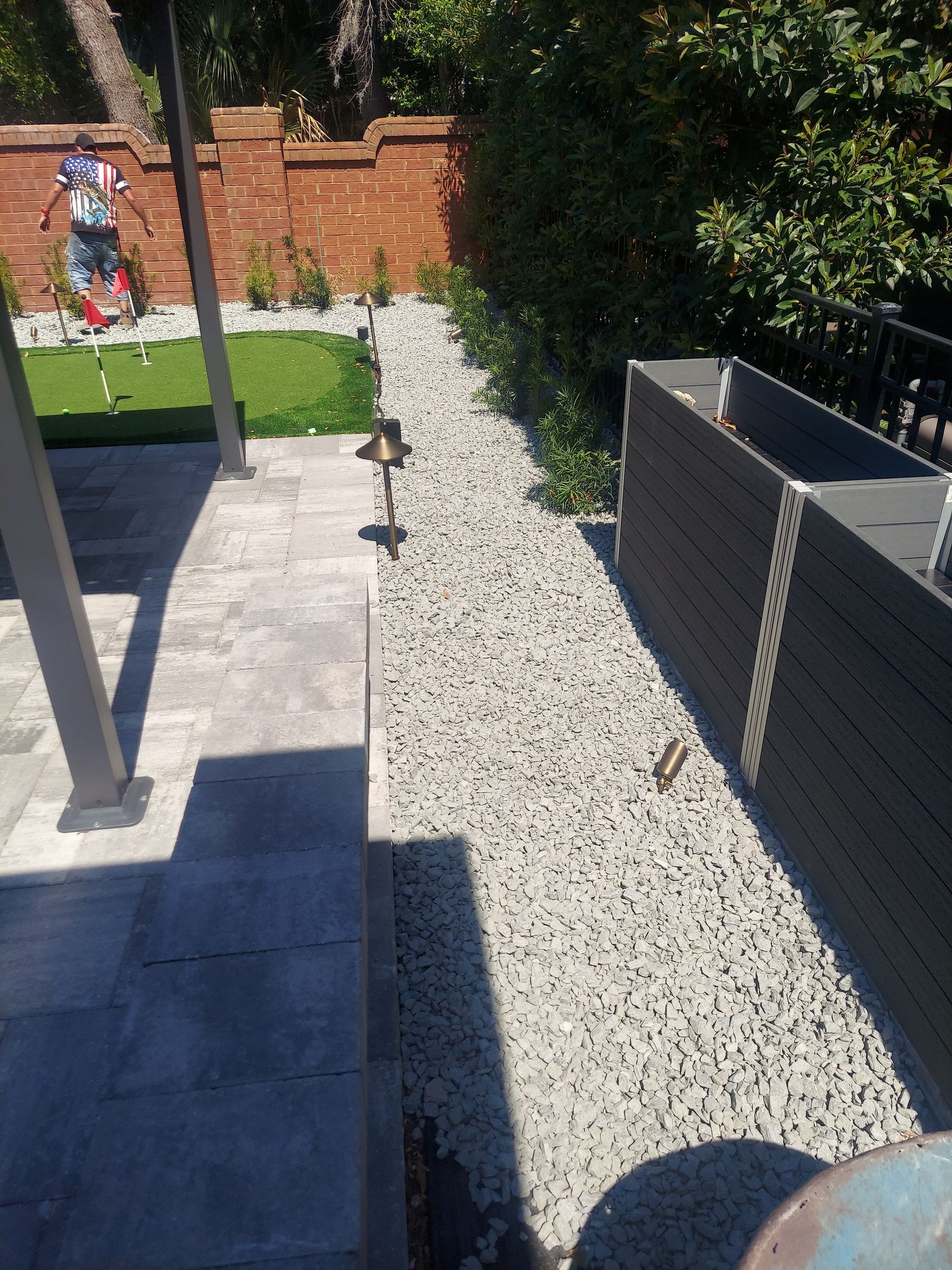 A gravel path in a backyard with a brick wall in the background