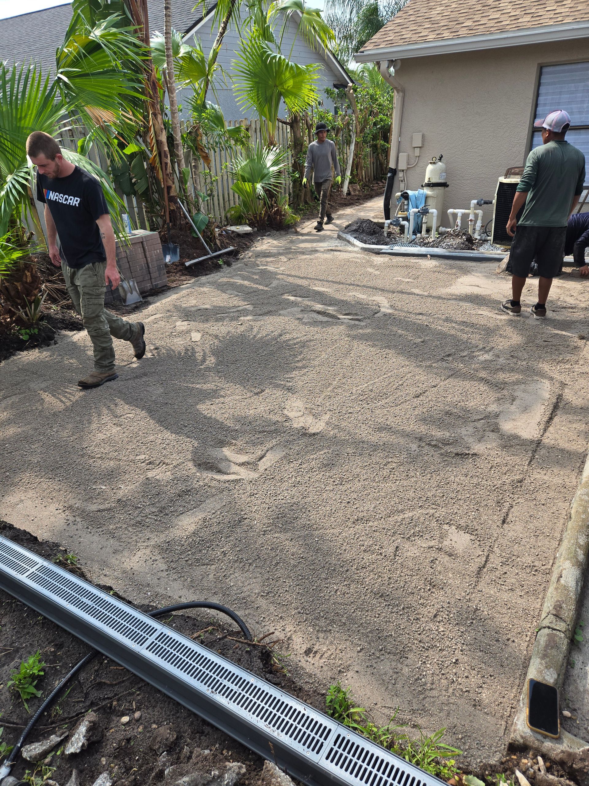 A group of men are working on a driveway in front of a house.