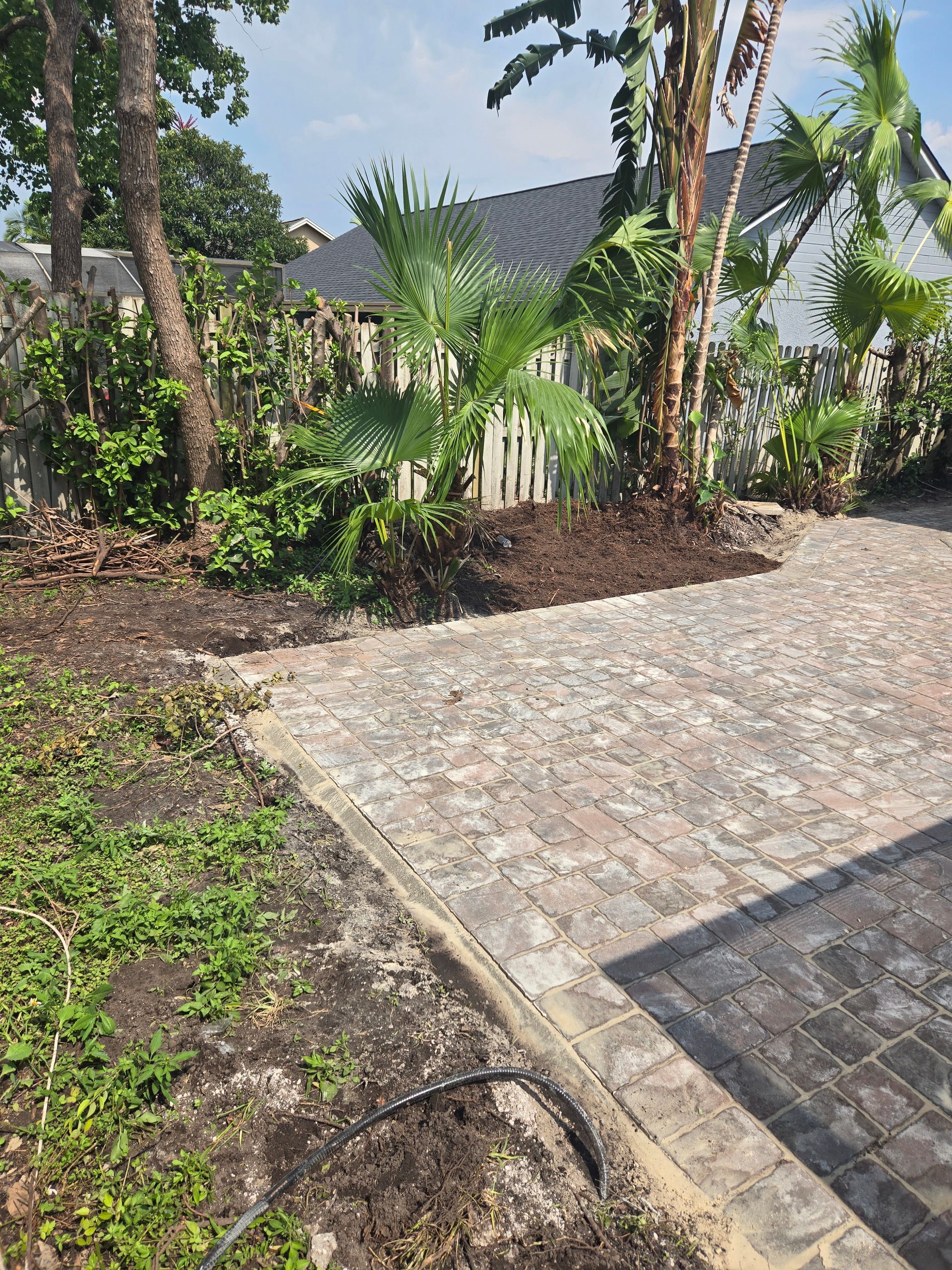 A brick driveway leading to a house surrounded by trees and bushes.