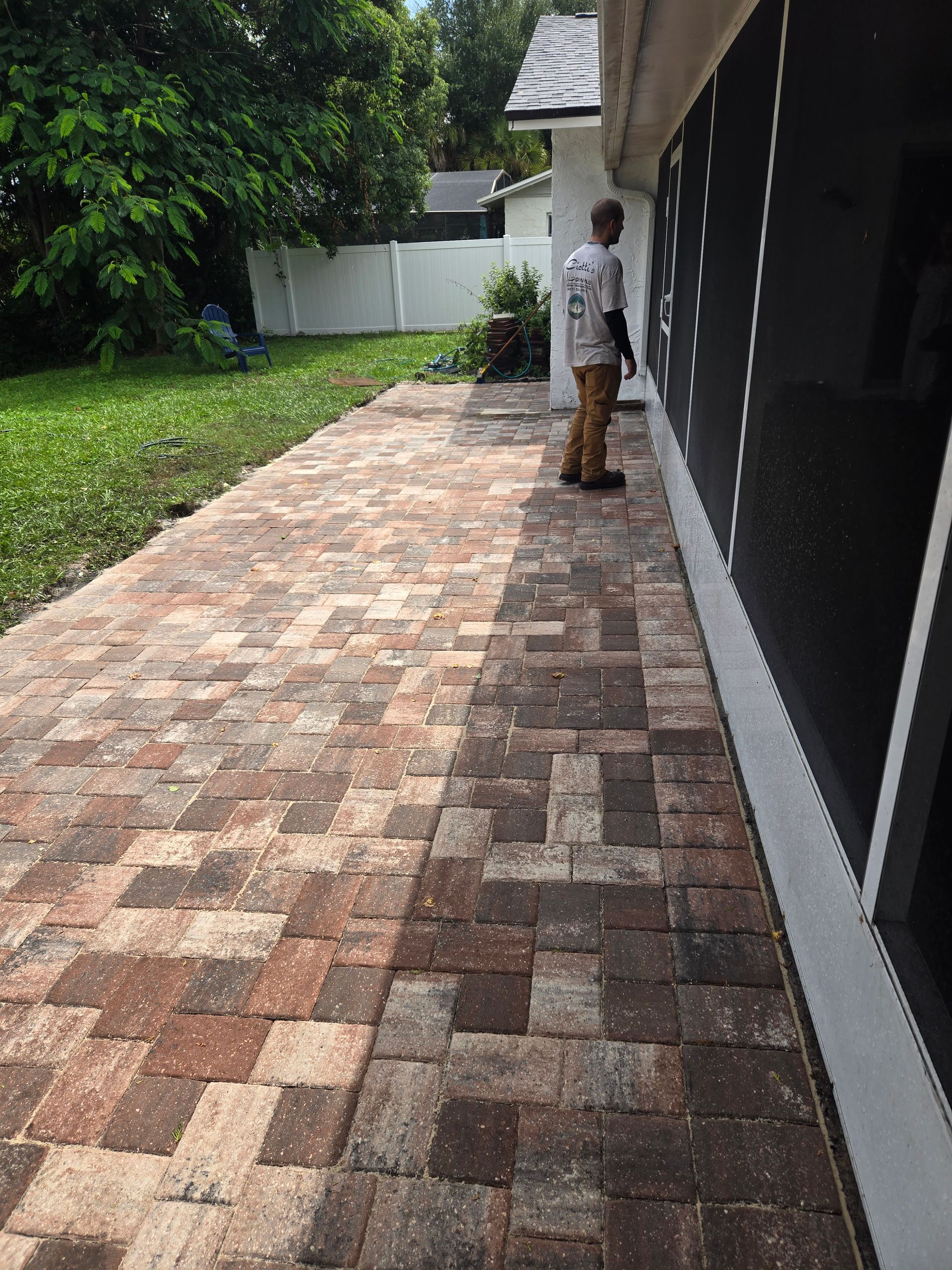 A man is standing on a brick walkway in front of a house.