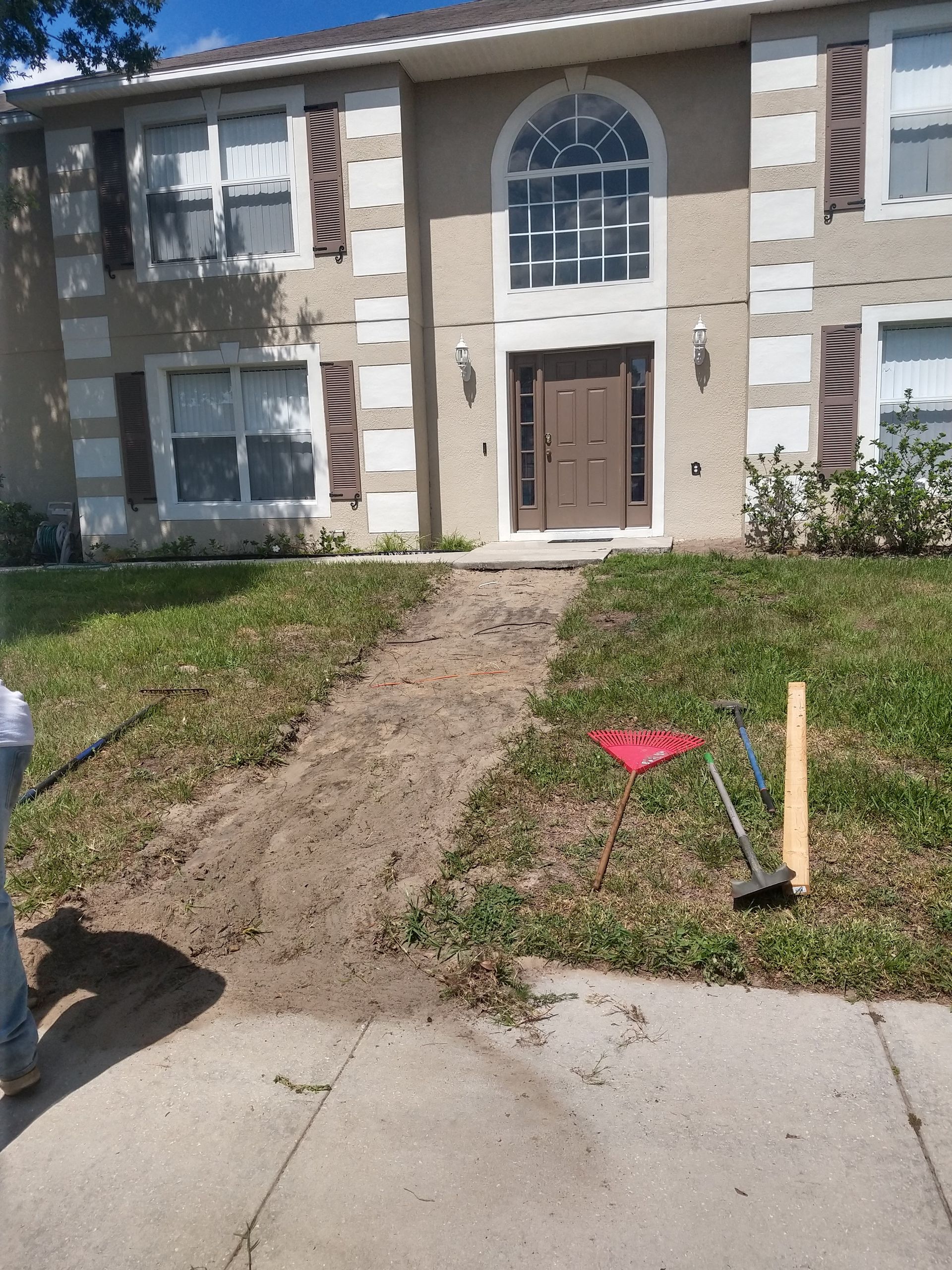 A man is shoveling dirt in front of a house
