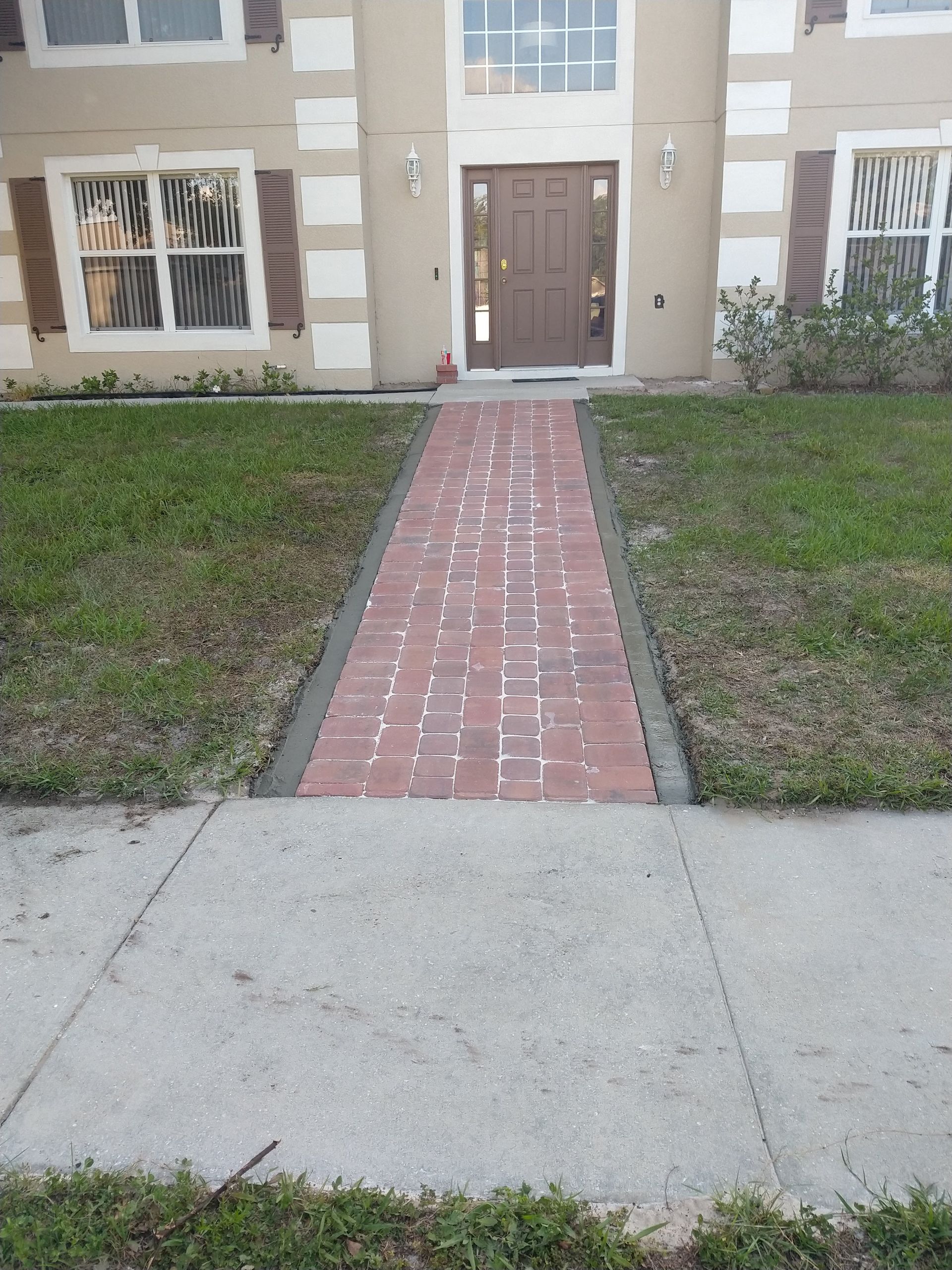 A brick walkway leads to the front door of a house