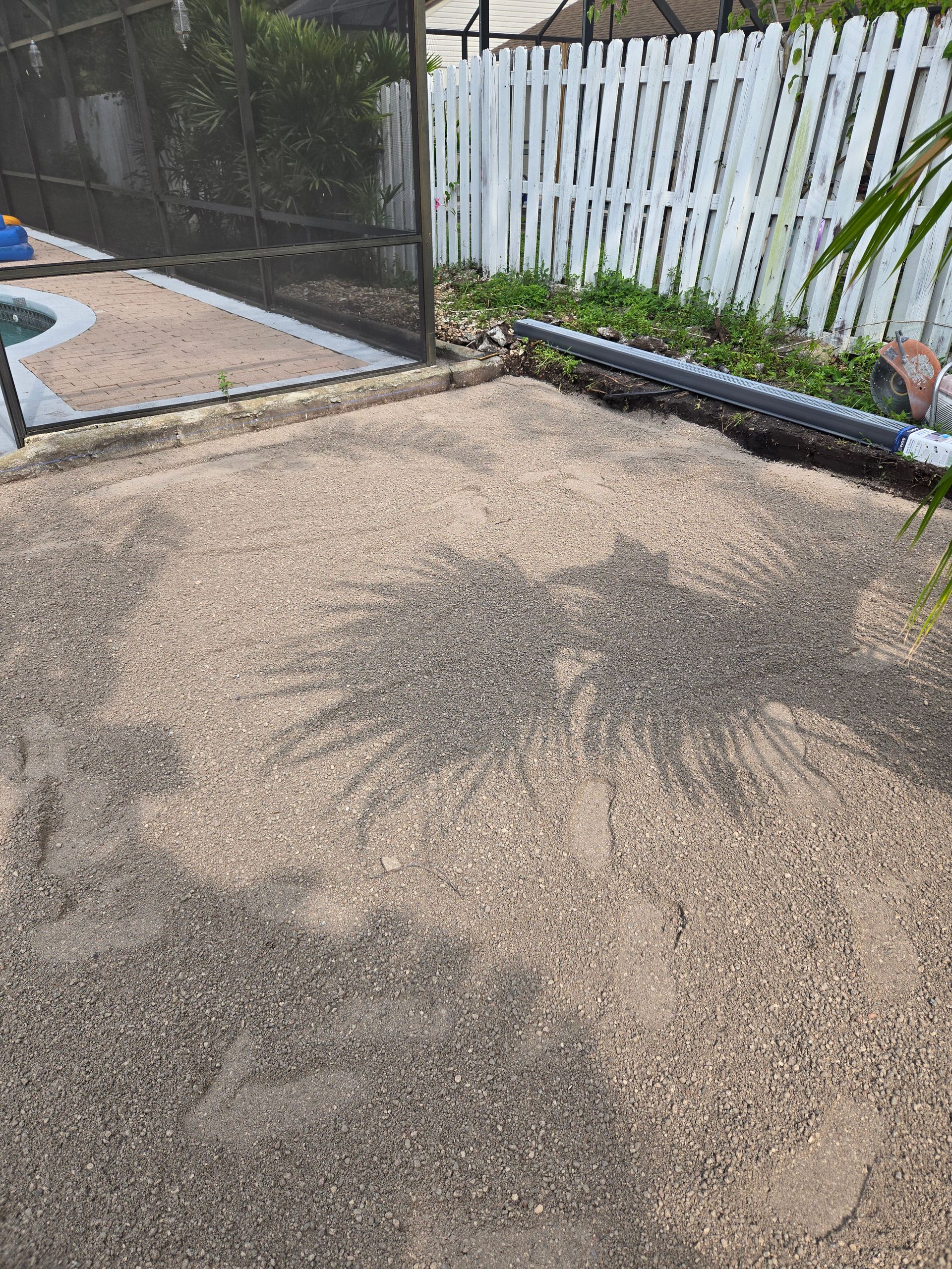 A pile of dirt is sitting in the middle of a backyard next to a pool.