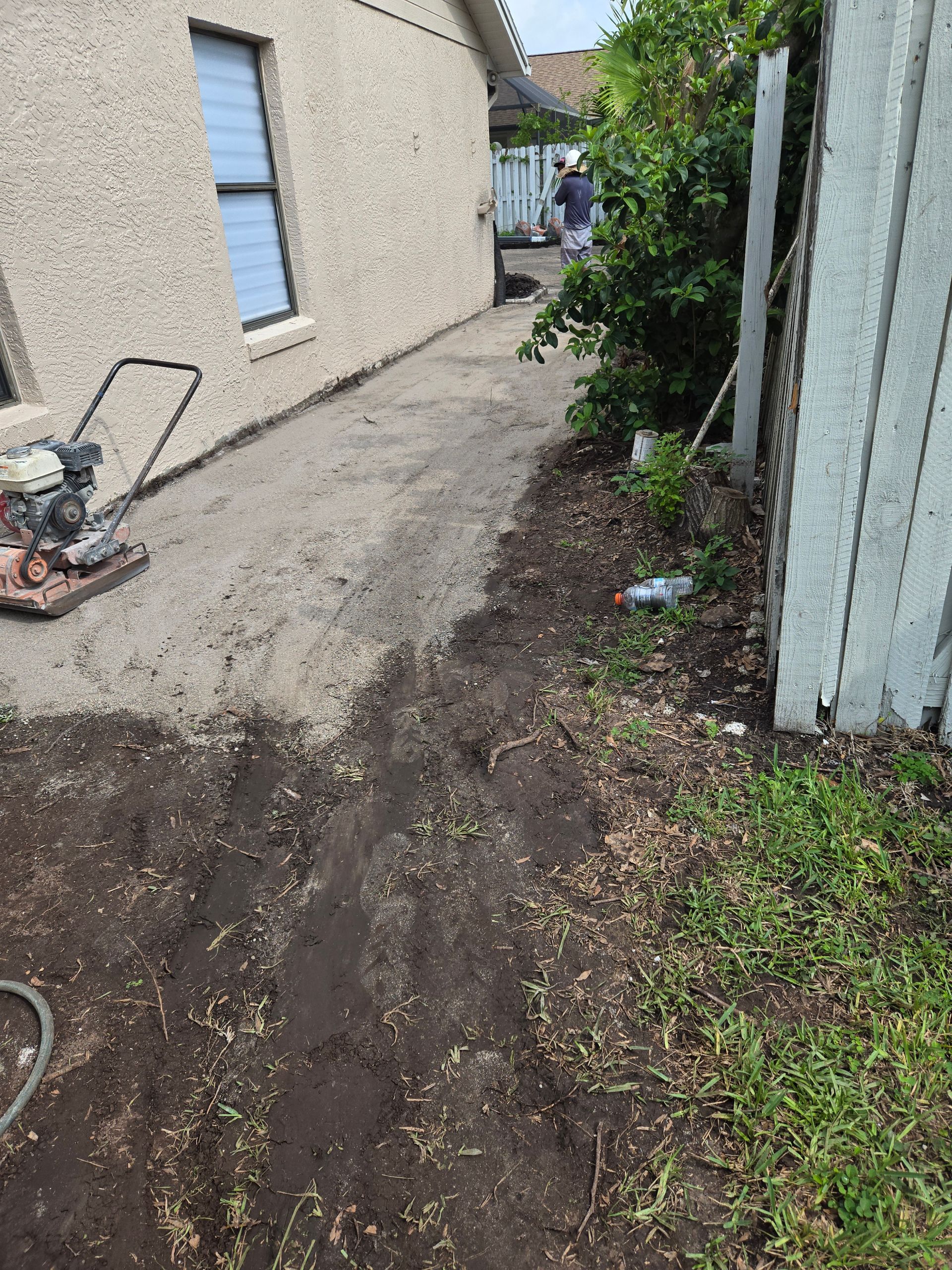 A lawn mower is sitting on top of a pile of dirt in front of a house.