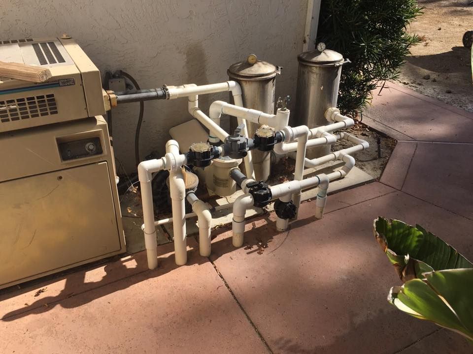 A bunch of pipes are sitting on the ground next to a machine