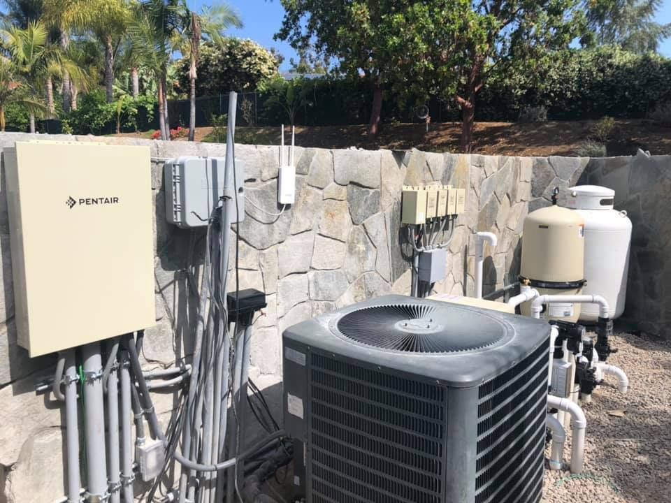 A large air conditioner is sitting in front of a stone wall.