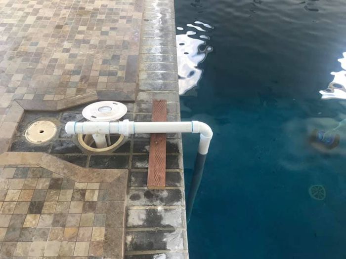 A pipe is attached to the side of a swimming pool.