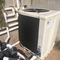 A black and white air conditioner is sitting on top of a pile of pipes.