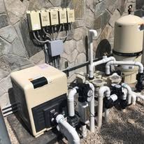 A swimming pool pump is sitting on top of a wooden table next to a stone wall.