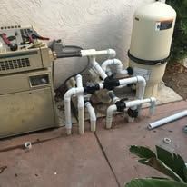 A pool heater is sitting on top of a concrete patio next to a water tank.
