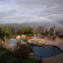There is a rainbow in the sky over a swimming pool.