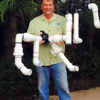 A man is holding a camera and a bunch of white pipes.