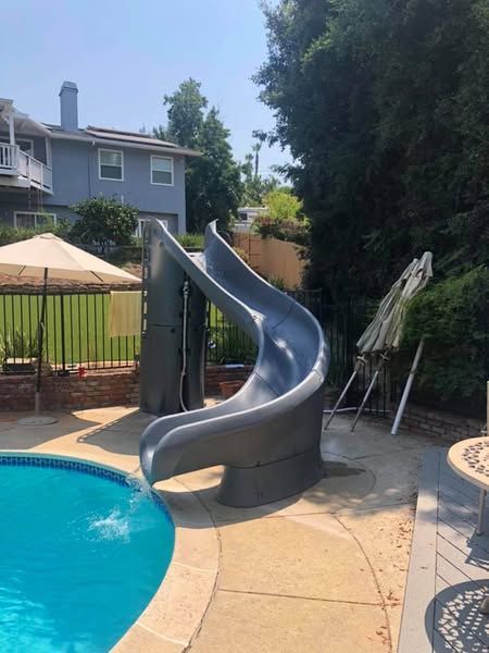 A swimming pool with a slide in the backyard