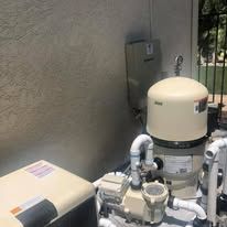 A swimming pool filter is sitting next to a wall.