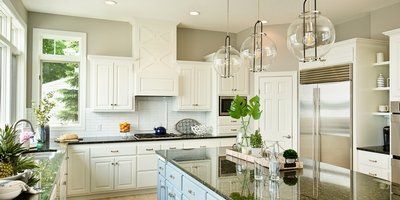 A kitchen with white cabinets , black counter tops , stainless steel appliances and a large island.