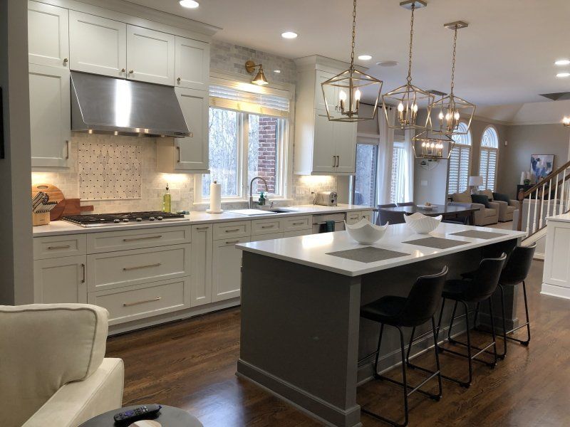 A kitchen with white cabinets and stainless steel appliances and a large island.
