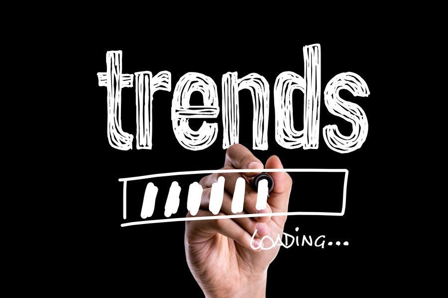 A hand is writing the word trends on a blackboard.